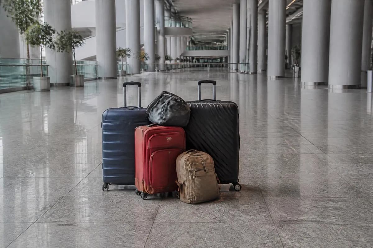 Terminal zemininde bir araya toplanmış üç valiz, bir sırt çantası ve bir seyahat çantası
